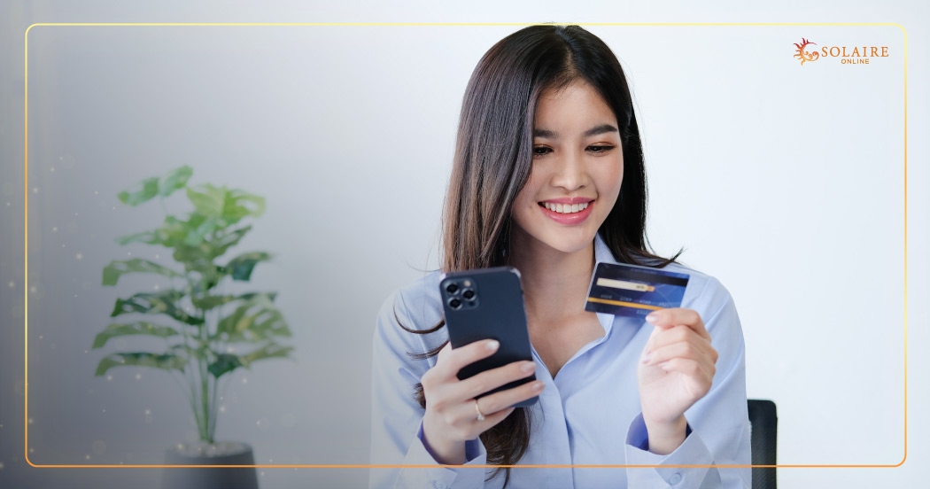 Solaire Online Casino Payment Methods Explained - A Woman Holding Her Phone And Card While Smiling